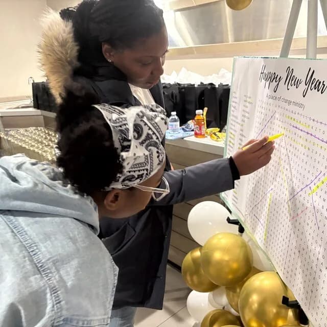 Two guests highlighting words on a giant personalized New Year word search at a party